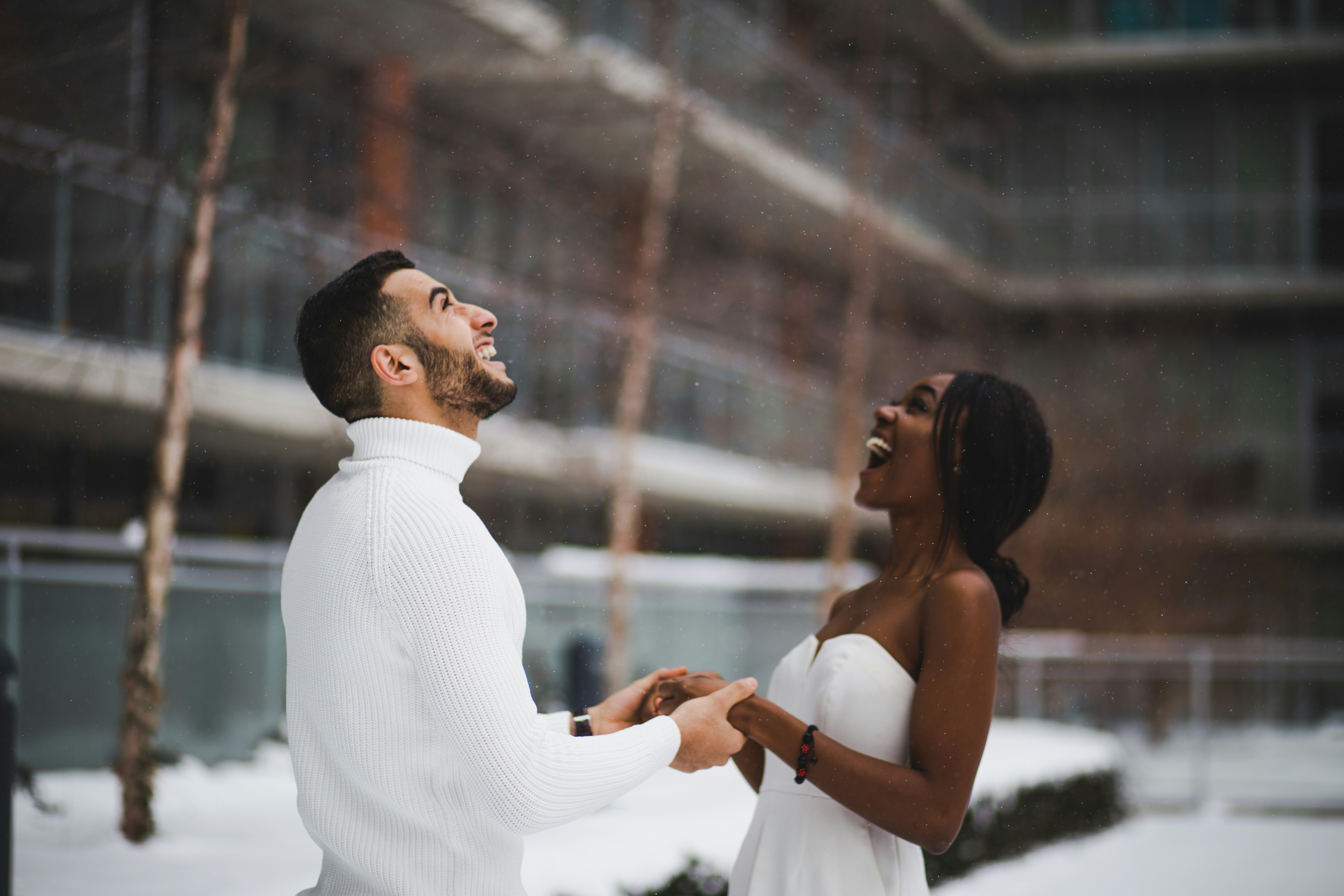 Newly engaged couple holding hands in a light snow