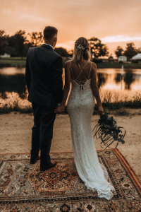 Bride and groom on waters edge during sunset